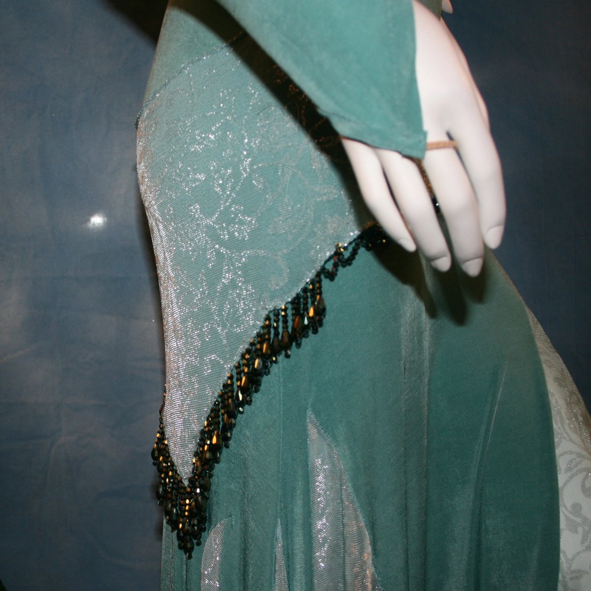 close detail view of Aqua social ballroom dress created in luxurious aqua solid slinky fabric with aqua iridescent sheer insets, embellished with hand beading of Swarovski beads on hip sash. Very full around bottom...can be a beginner ballroom dancer smooth ballroom dress.