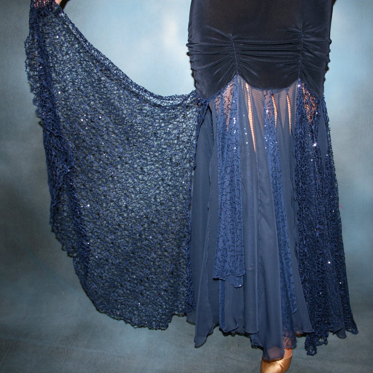 Crystal's Creations lower view of Ballroom dress created in luxurious navy blue solid slinky fabric with yards of gorgeous unique sequined mermaid net look lace & chiffon. The bottom of base of dress has ruching at the hip. A great social dress for any ballroom dance or special occasion, as well as a great beginner show dress!