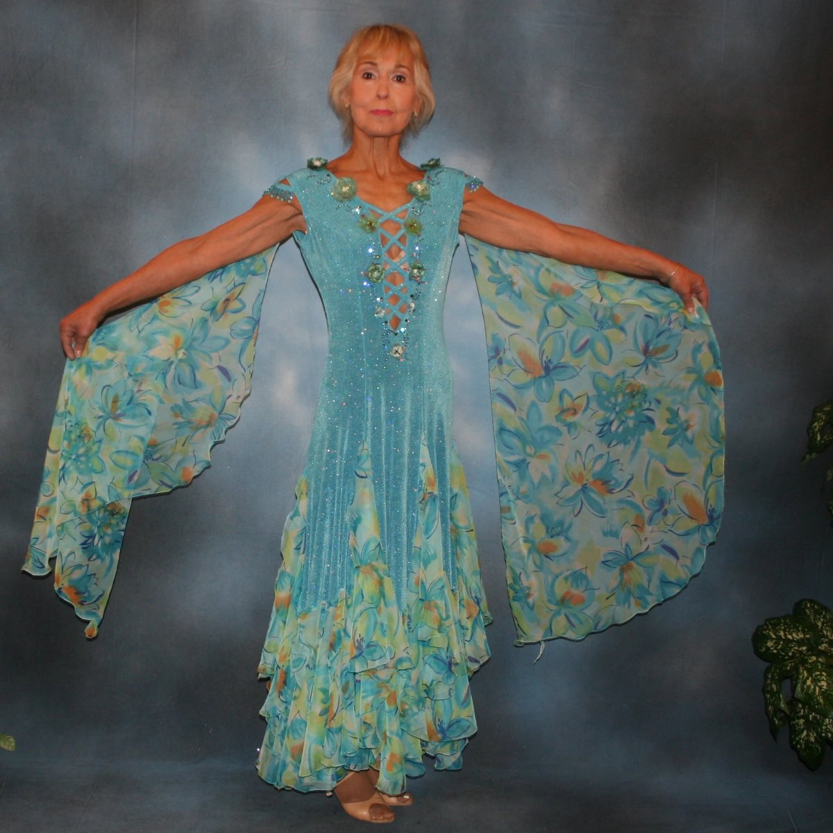 Turquoise ballroom dress of turquoise glitter slinky features lattice work detailing with yards & yards of print chiffon, enhanced with velveteen flowers plus aquamarine Swarovski rhinestones, hand beading on shoulder detailing... with detachable floats.