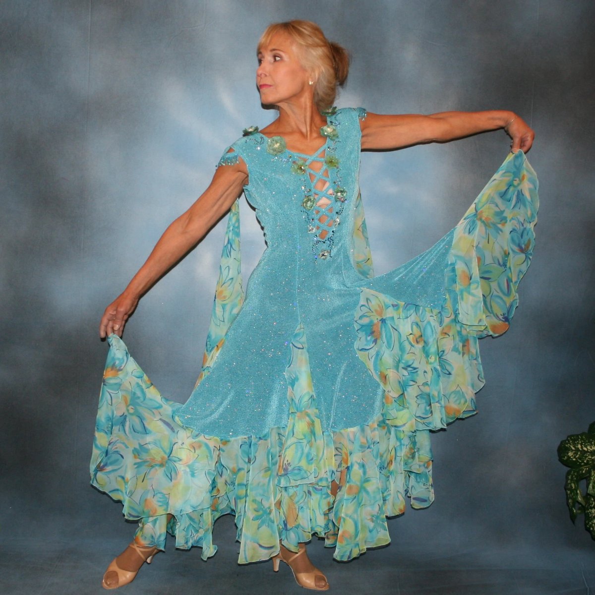 Turquoise ballroom dress of turquoise glitter slinky features lattice work detailing with yards & yards of print chiffon, enhanced with velveteen flowers plus aquamarine Swarovski rhinestones, hand beading on shoulder detailing... with detachable floats.