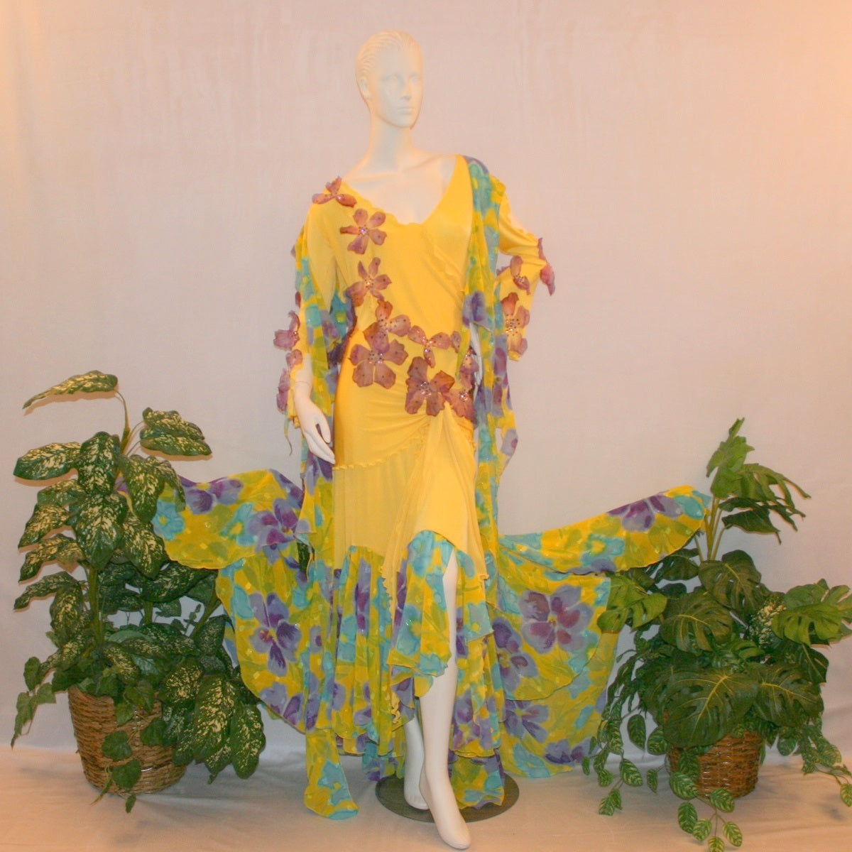 Crystal's Creations Yellow ballroom dress created of luxurious yellow slinky with yards of flower printed textured chiffon of yellow, orchids & blues is embellished with deep orchid silk flowers that have rhinestone work in shades of orchid.