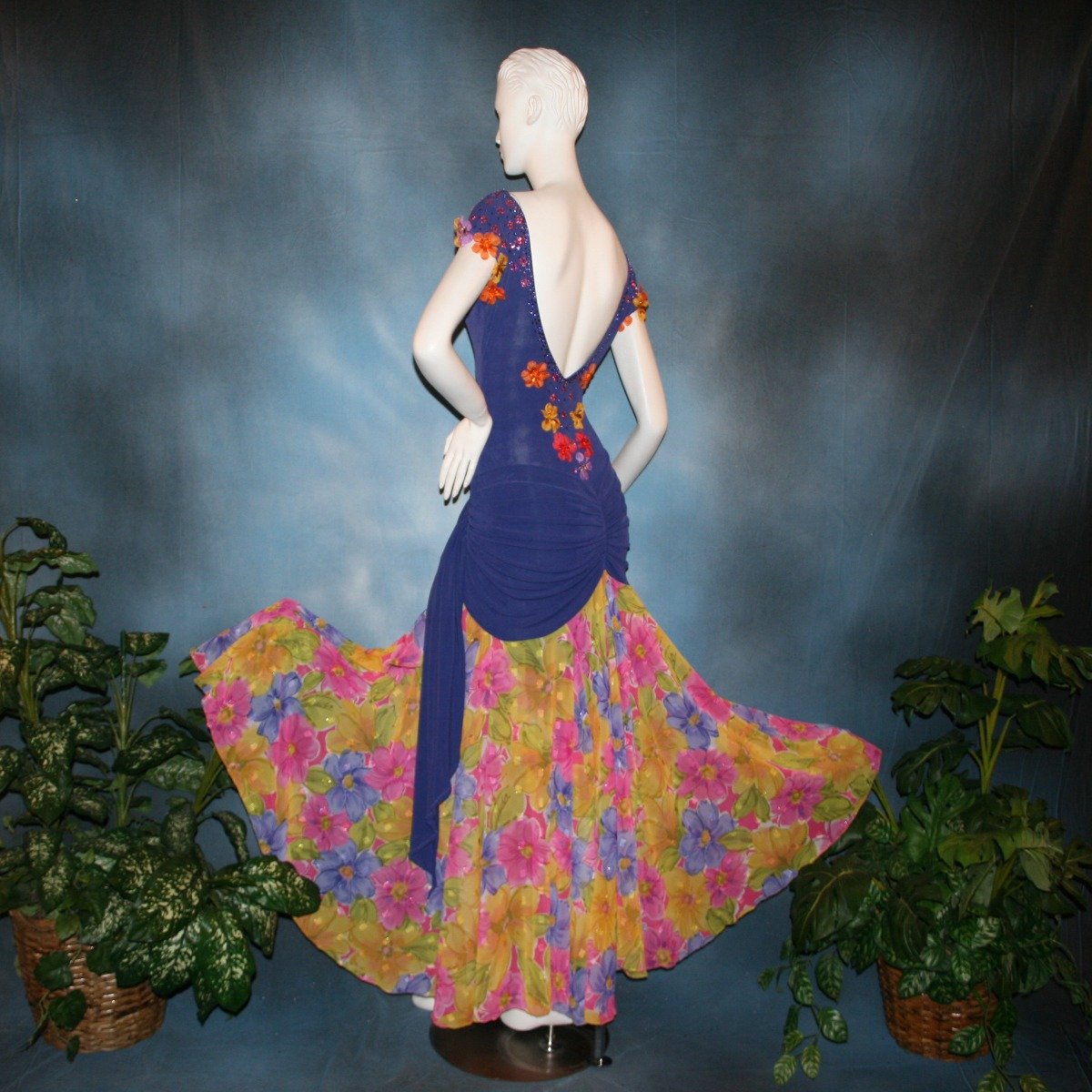 Crystal's Creations back view of Converta ballroom dress featuring a Latin/rhythm dress created in luxurious deep perwinkle solid slinky with lots of flounces in accents of a floral chiffon in yellow with pinks & purples 