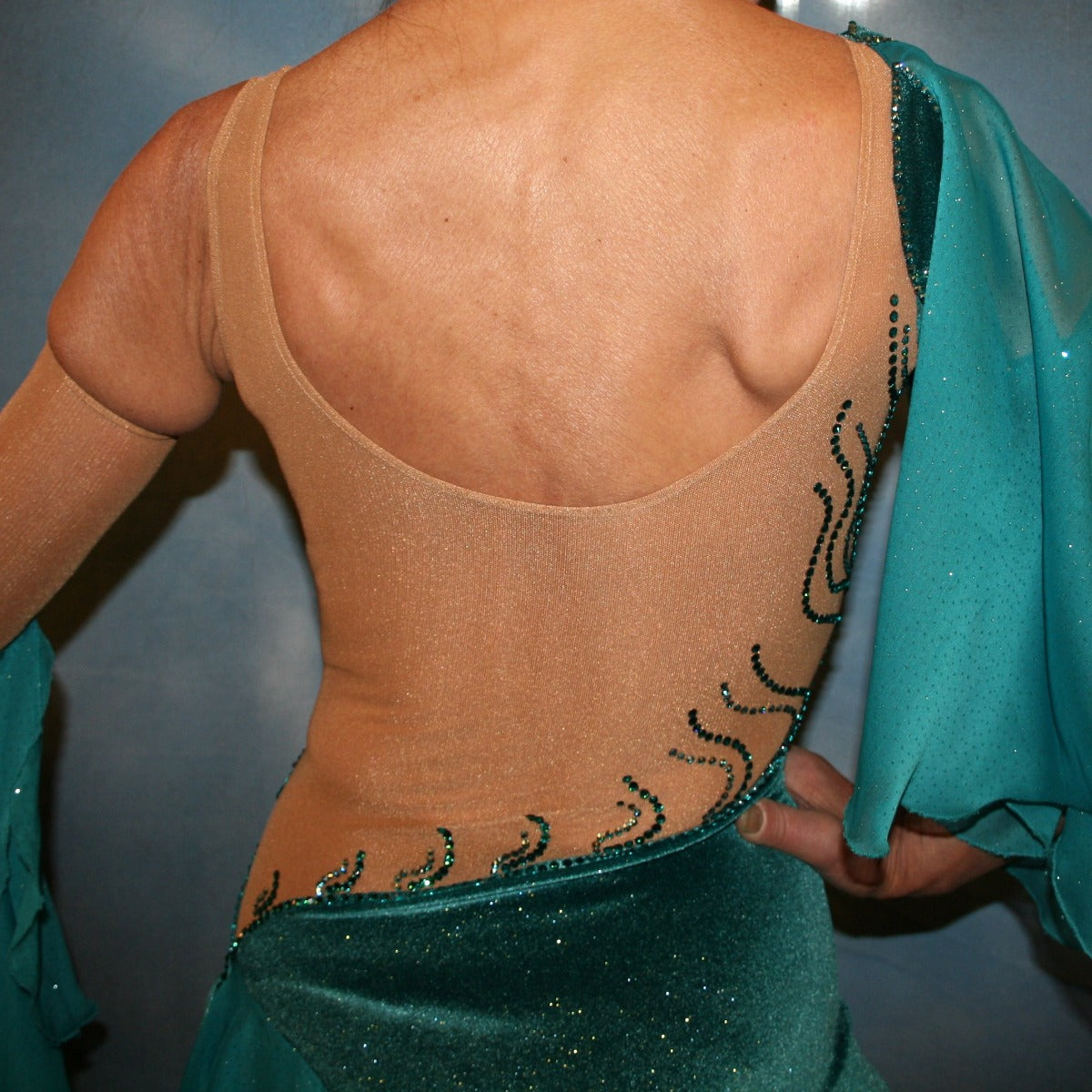 Crystal's Creations close up back view of Teal Latin/rhythm dress was created on a nude illusion base with luxurious teal glitter stretch velvet fabric along with flounces of teal glitter chiffon, embellished with blue zircon & blue zircon Ab Swarovski stonework plus hand beaded detailing