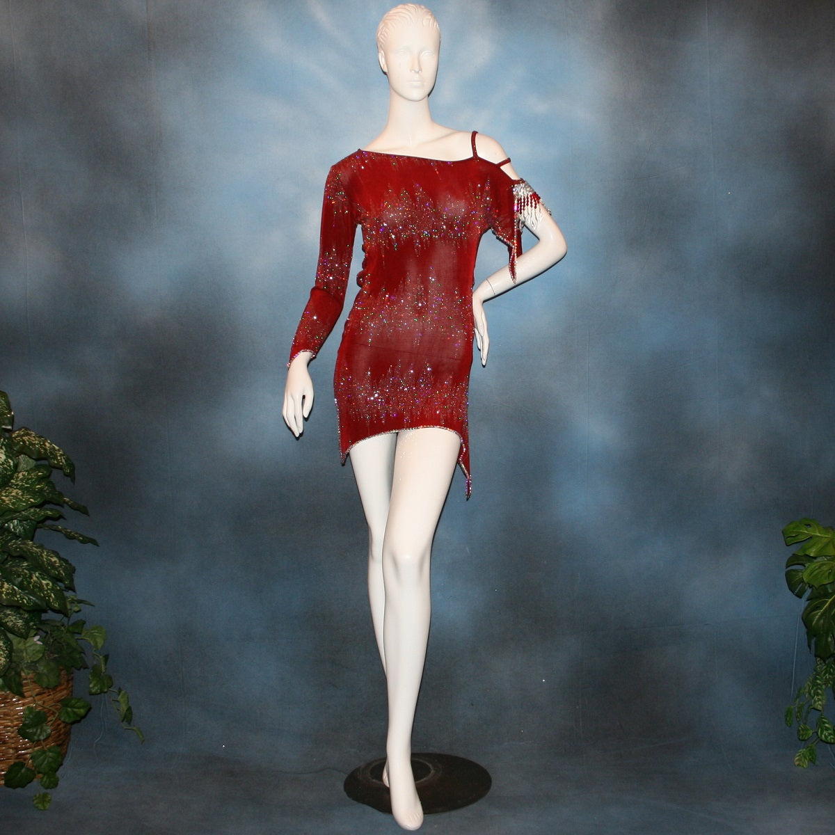 Deep scarlette red Latin rhythm dress created in glitter slinky with an awesome electrifying glitter pattern features lattice detailing in the sides, one long sleeve & interesting detailing on the opposite shoulder with Swarovski hand beading & Crystal Ab rhinestone work edging the skirting, split cape sleeve & long sleeve.