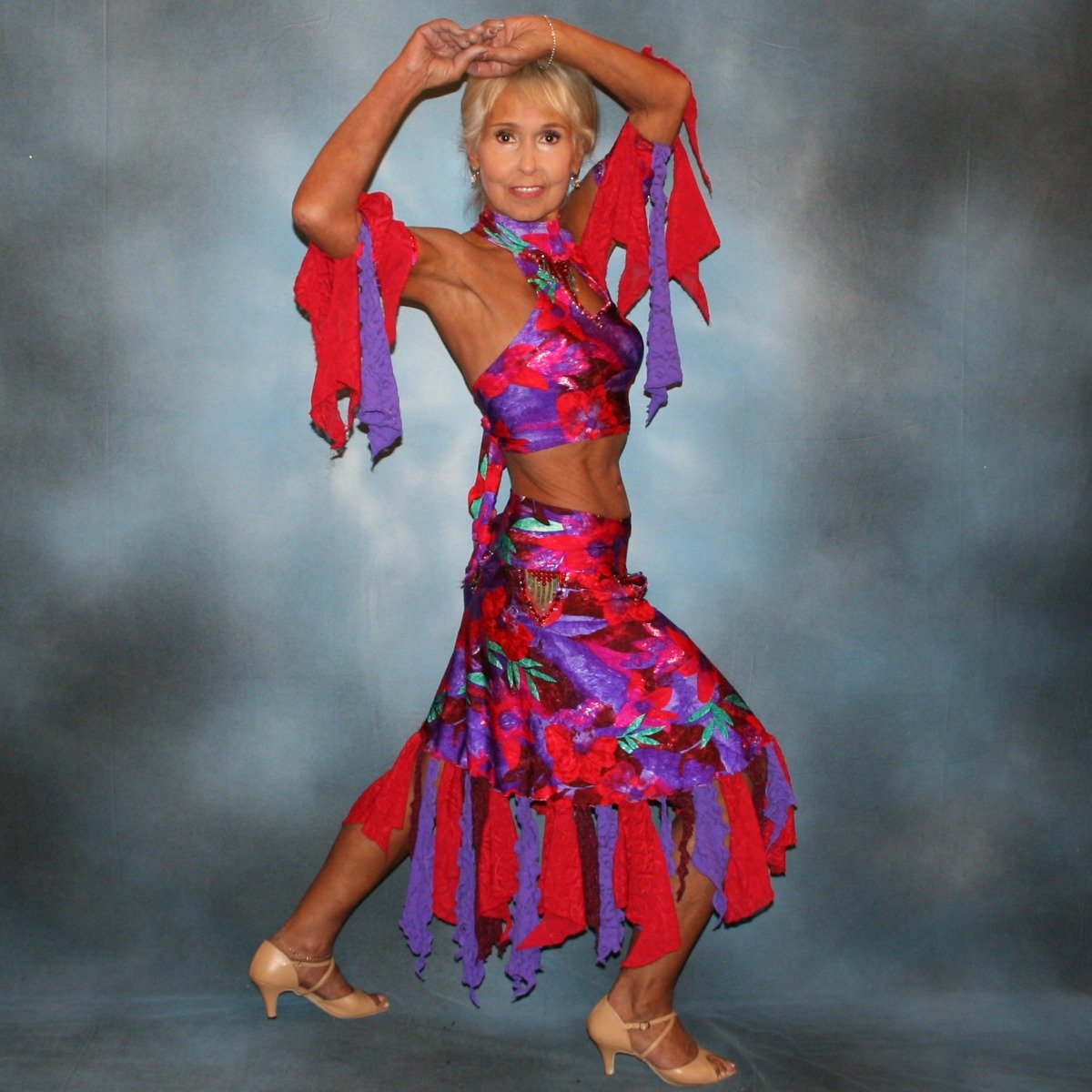 Crystal's Creations Red & purple tropical print 2 piece Latin/rhythm dress was created in tropical print lycra in deep reds,purples & a touch of green, along with accents of deep red textured chiffon scarf cut flounces & purple stretch lace petal cut flounces on skirt and arm bands,