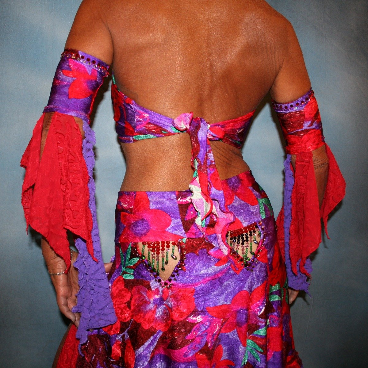 Crystal's Creations back close up view of Red & purple tropical print 2 piece Latin/rhythm dress was created in tropical print lycra in deep reds,purples & a touch of green, along with accents of deep red textured chiffon scarf cut flounces & purple stretch lace petal cut flounces on skirt and arm bands,
