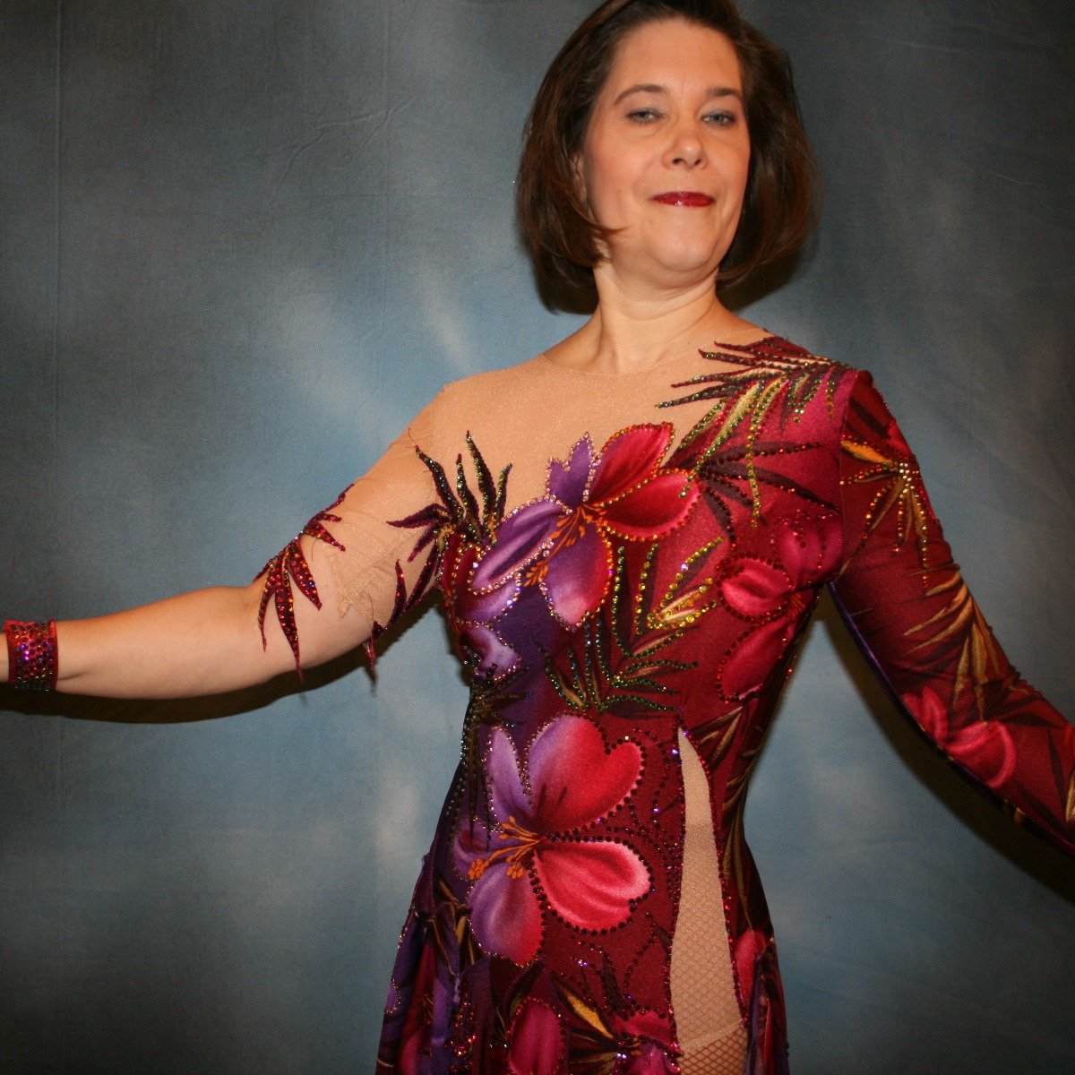 close front view of Tropical print Latin/rhythm dress created in tropical print lycra in burgundies & purples on a nude illusion base, embellished lavishly with Swarovski rhinestone work in burgundies, purples, orchids & a touch of the greens & golds that are within the print.
