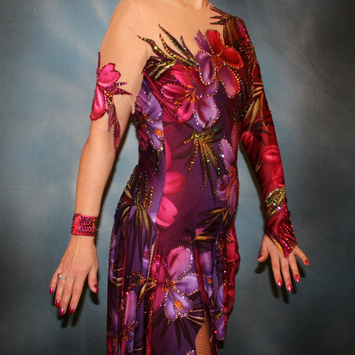 close side view of Tropical print Latin/rhythm dress created in tropical print lycra in burgundies & purples on a nude illusion base, embellished lavishly with Swarovski rhinestone work in burgundies, purples, orchids & a touch of the greens & golds that are within the print.