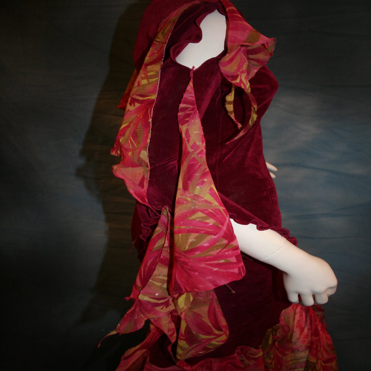 close side view of Cranberry sleek social Latin/rhythm dress created in luxurious cranberry solid slinky fabric with printed sheer flounces & floats. 