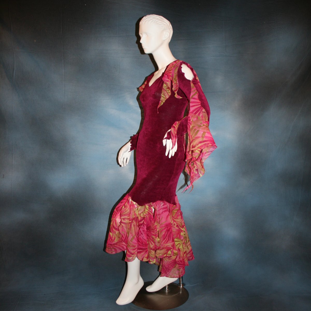 left side view of Cranberry sleek social Latin/rhythm dress created in luxurious cranberry solid slinky fabric with printed sheer flounces & floats. 