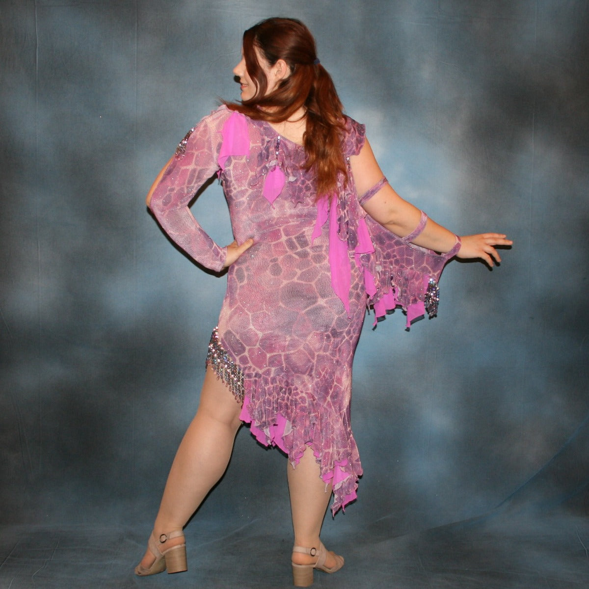 Crystal's Creations back view of Orchid Latin/rhythm dress created of wild orchid & violet printed glitter slinky has orchid accents, flounces on one arm & skirt, embellished with Swarovski hand beading of various shades of orchid & shapes through out, is a fun & colorful Latin/rhythm dress