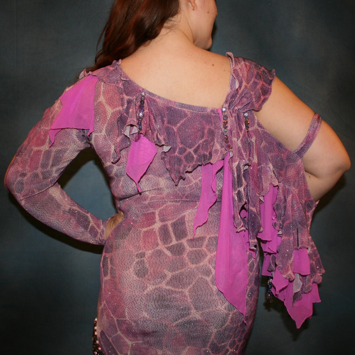 Crystal's Creations close back view of Orchid Latin/rhythm dress created of wild orchid & violet printed glitter slinky has orchid accents, flounces on one arm & skirt, embellished with Swarovski hand beading of various shades of orchid & shapes through out, is a fun & colorful Latin/rhythm dress